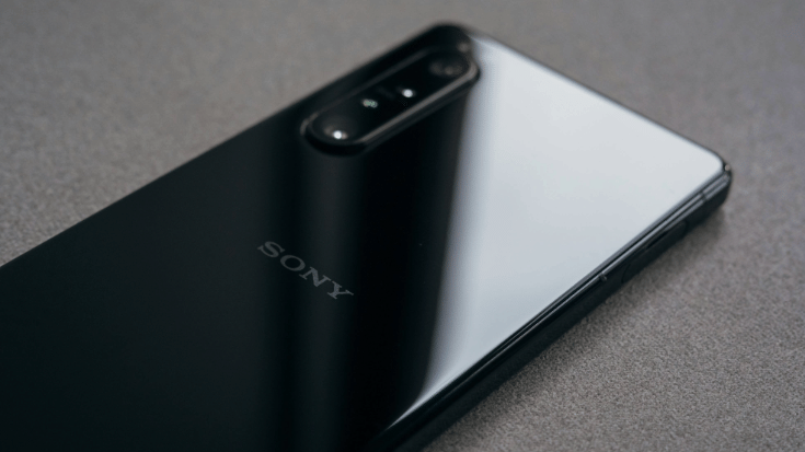 A colour photograph showing a close-up of a Sony Xperia Series Two phone model in back, against a brown table. you can only see the back of the phone, as it's lying face-down on the table. To illustrate a blog post entitled 'Does Sony Xperia Support eSIM Technology? .'