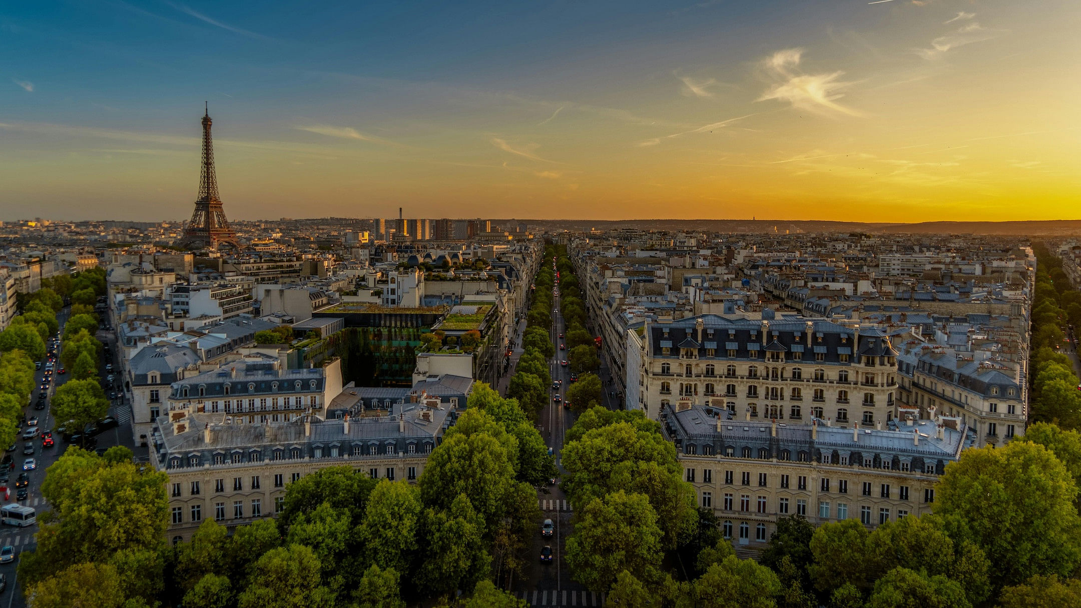 A stunning city view of Paris at sunset depicting the Eiffel Tower on the left and the setting sun on the right