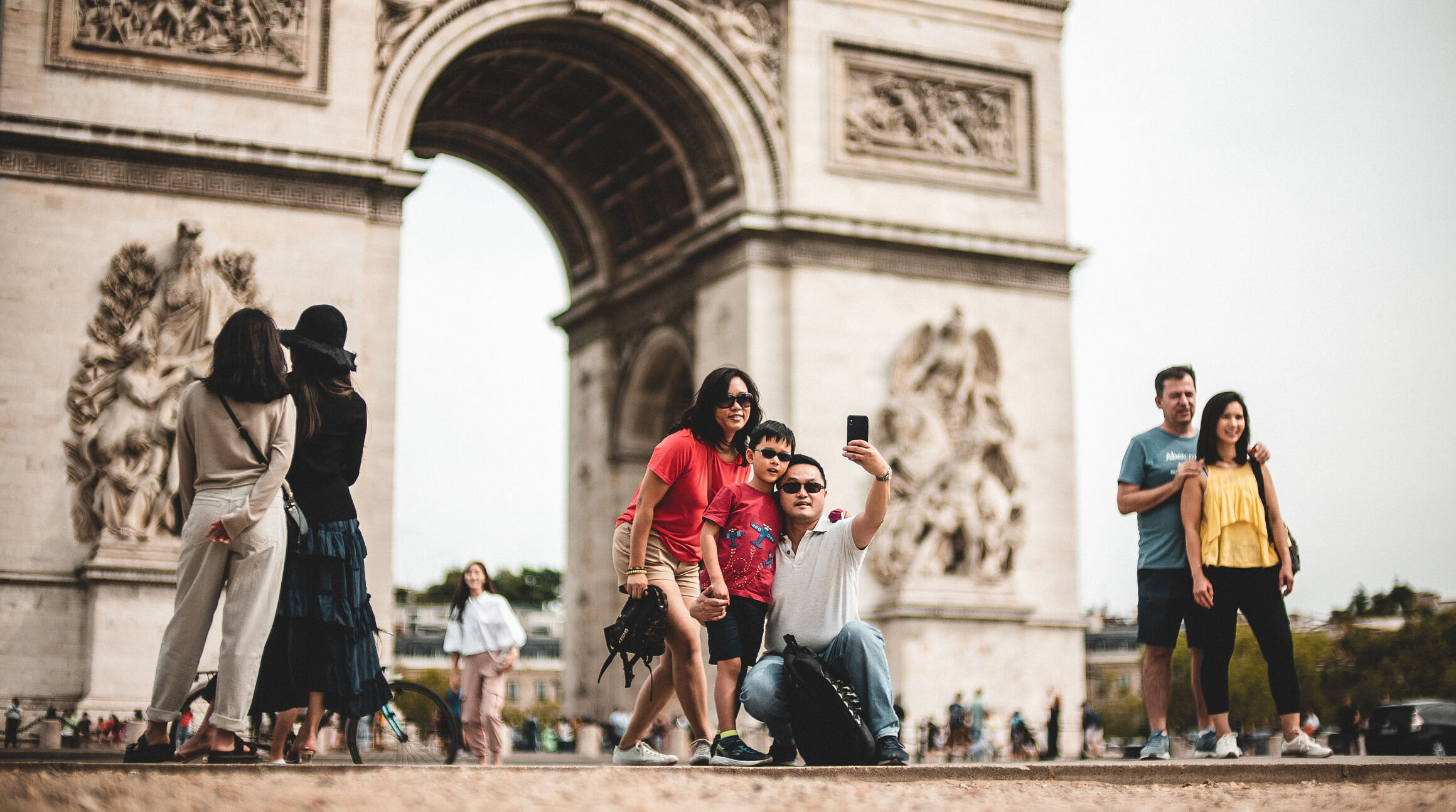 Family taking a selfie in front of Arc de Triomphe in Paris, France