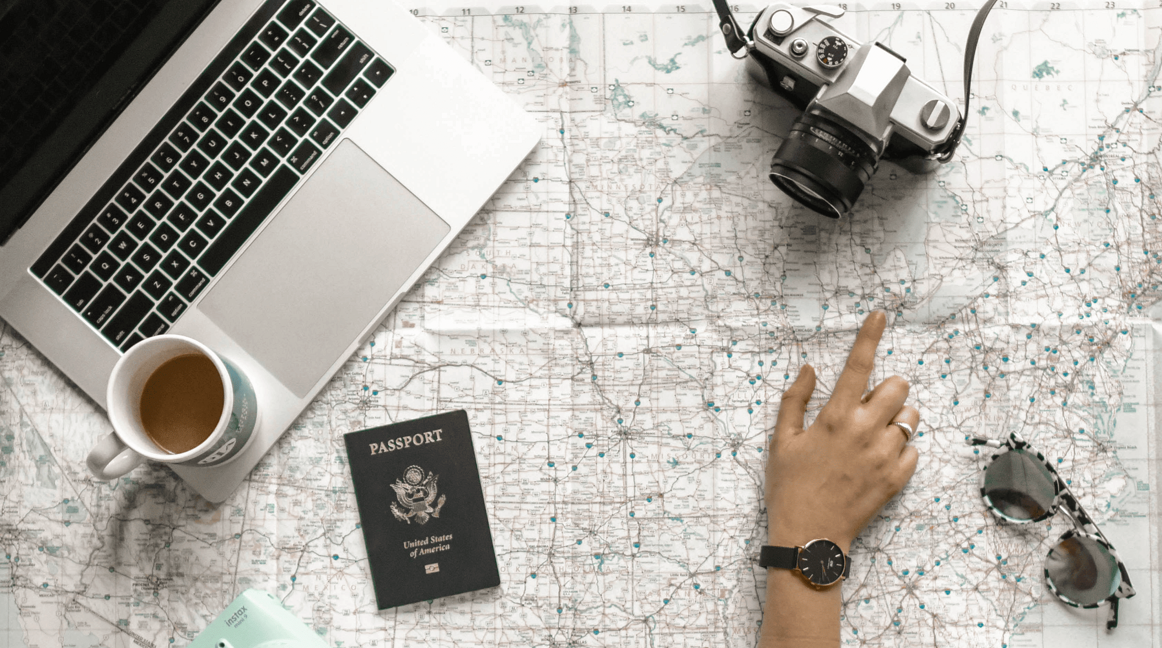 travel planning with world map, computer, camera, and passport