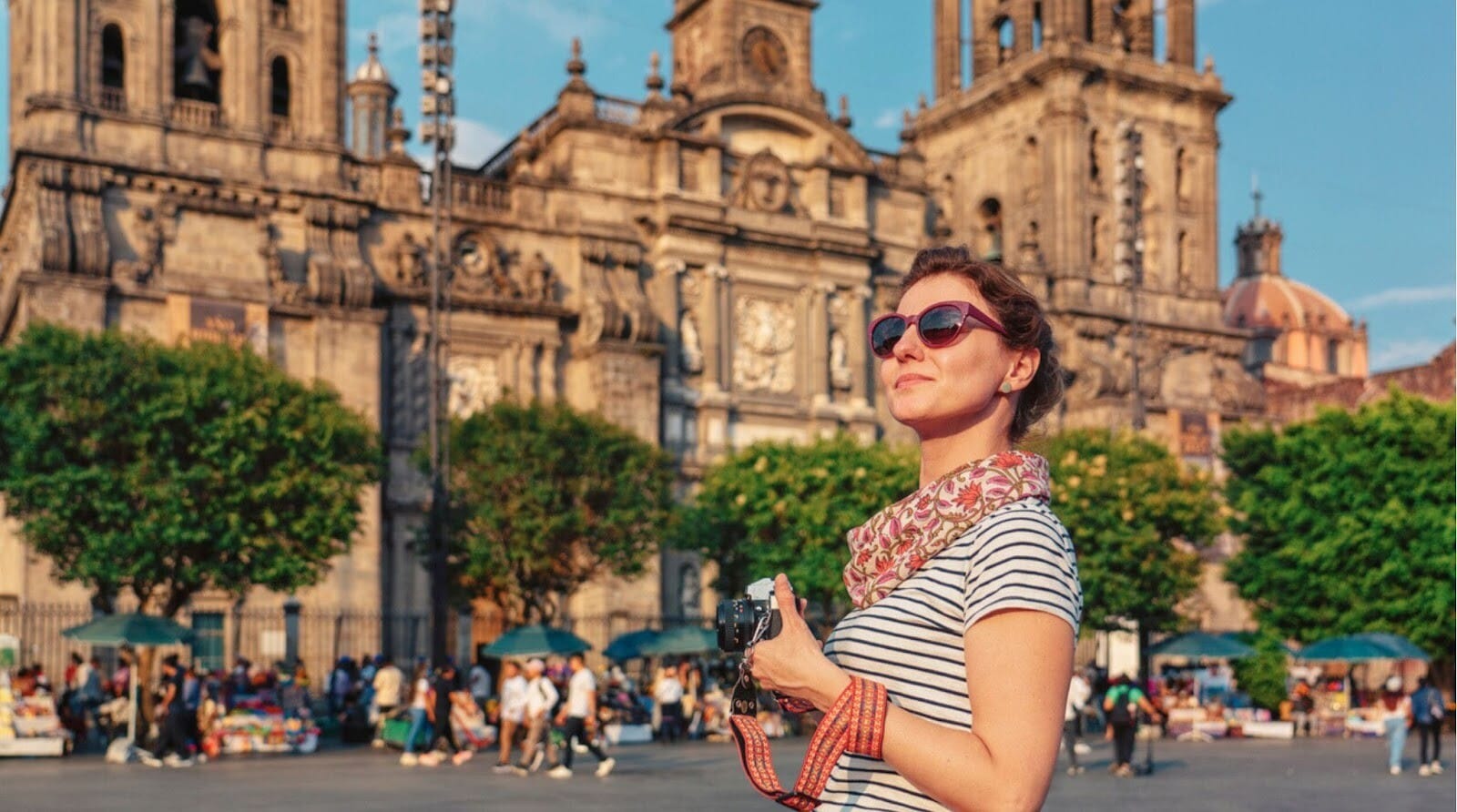 Mulher tirando fotos com uma câmera analógica vintage no Zócalo, a praça principal, e na Catedral Metropolitana da Cidade do México durante o pôr do sol.