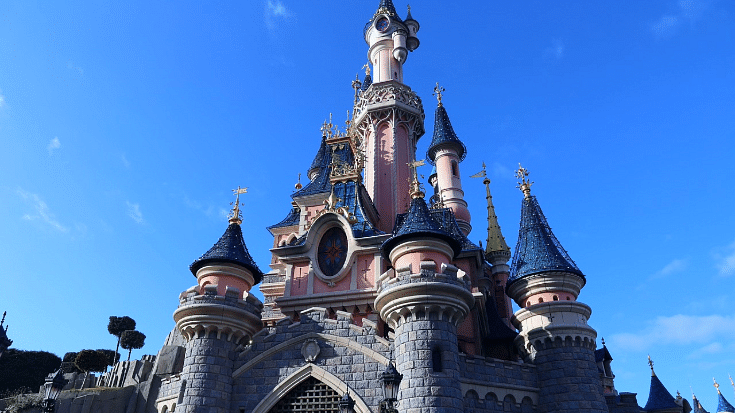 An image of a man-made pink castle with several towers and pointed roofs against a bright blue sky in the middle of Disneyland Paris to illustrate a blog post entitled The Best Family Winter Holidays from Ireland. 