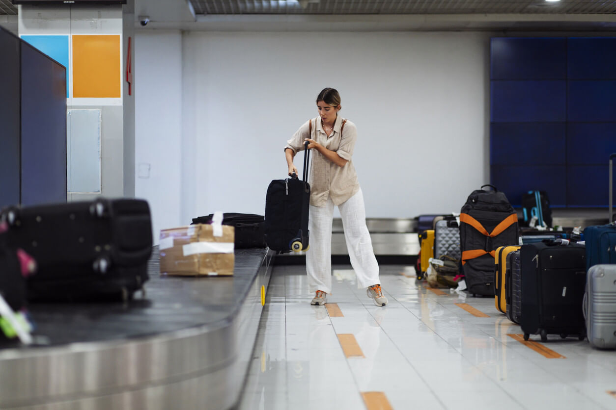 Woman grabbing her suitcase from the carousel at the airport